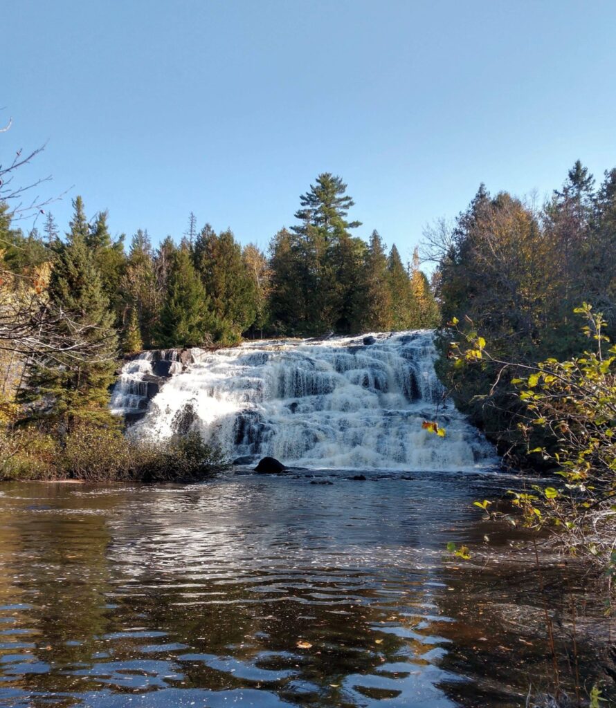 Scenic cascading waterfall surrounded by forest.