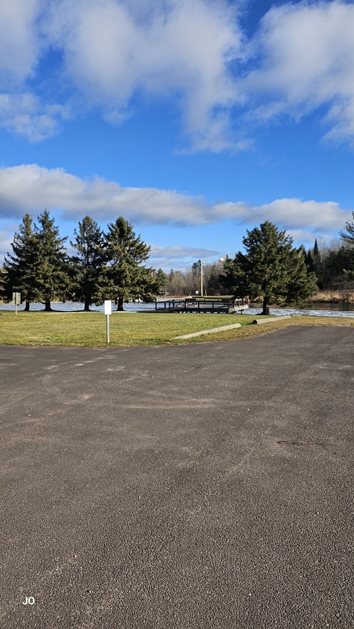 Sunny park with trees, clouds, and walking trail.