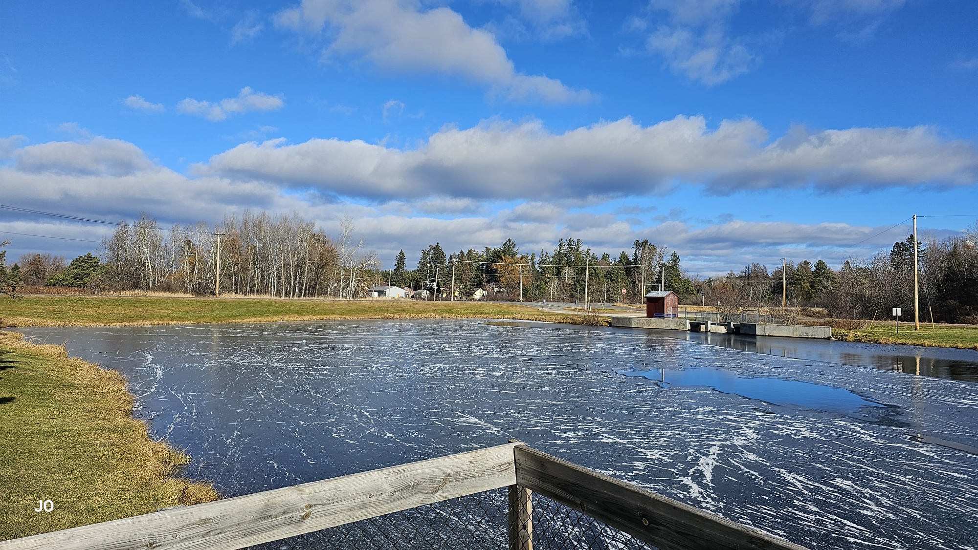 Sunny day over semi-frozen pond with clear sky