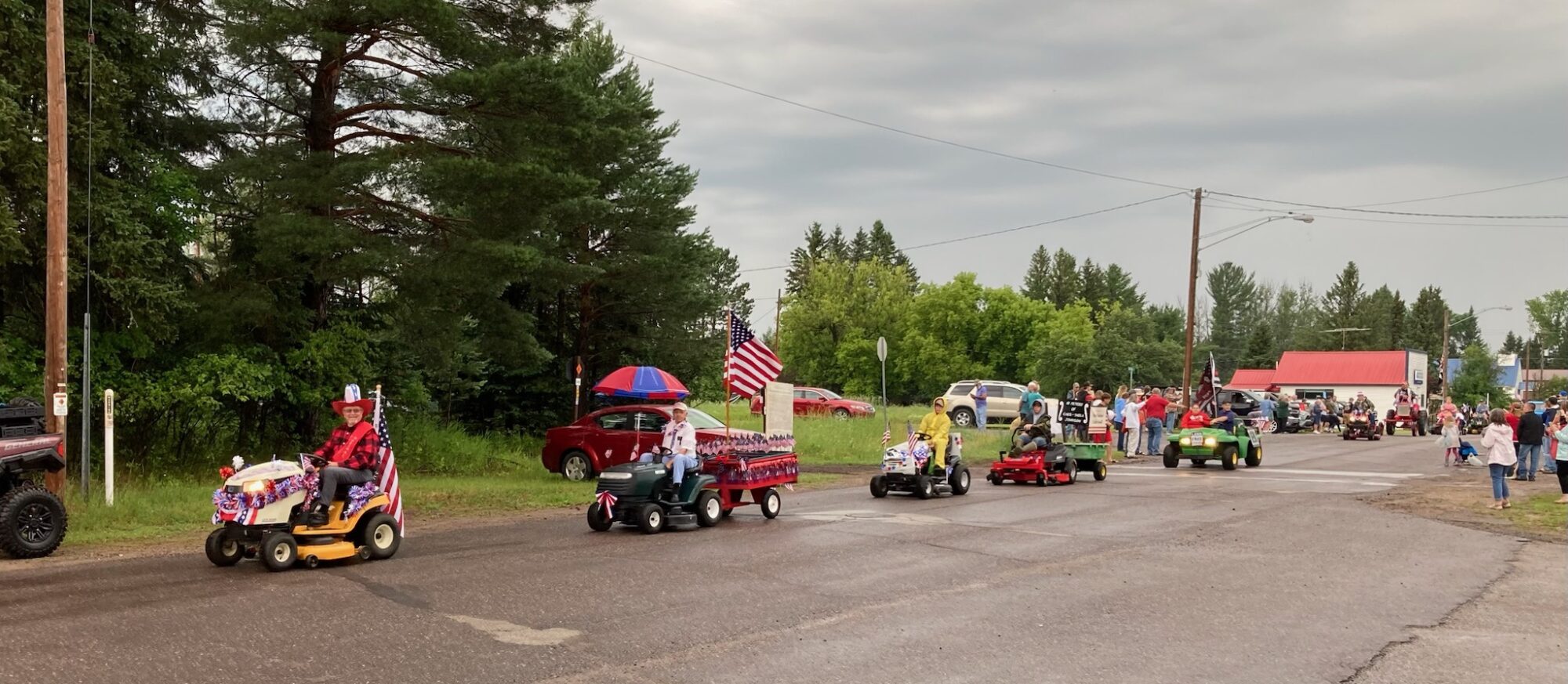 Small-town parade with decorated vehicles and American flags.