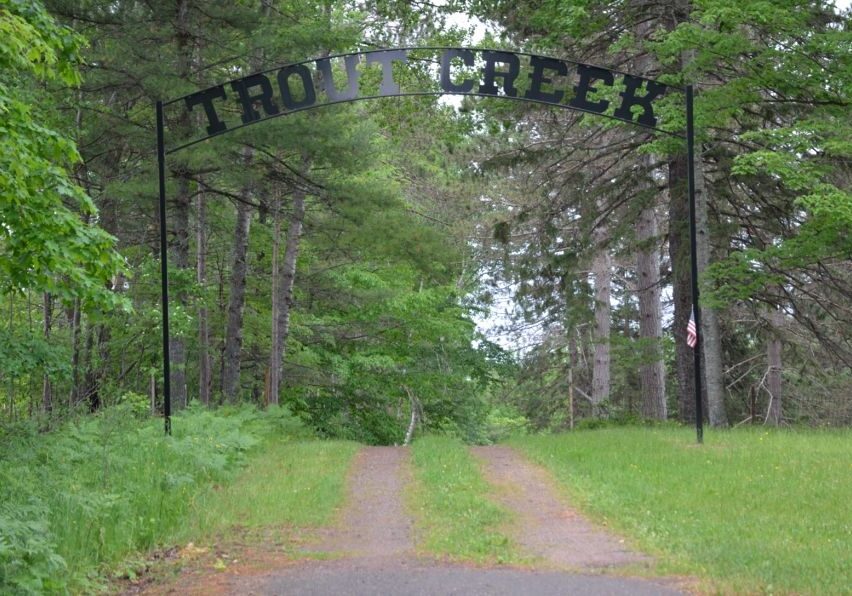 Trout Creek archway over forest path with American flag