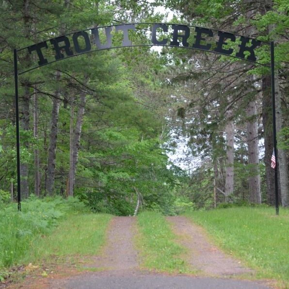 Trout Creek archway over forest path with American flag